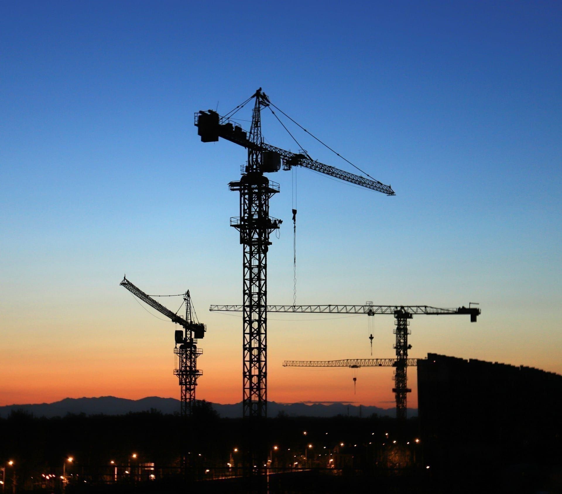 Tower cranes over a construction site at dusk